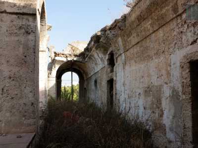 Percorriamo il portico che circonda la struttura, facendoci largo tra le sterpaglie...